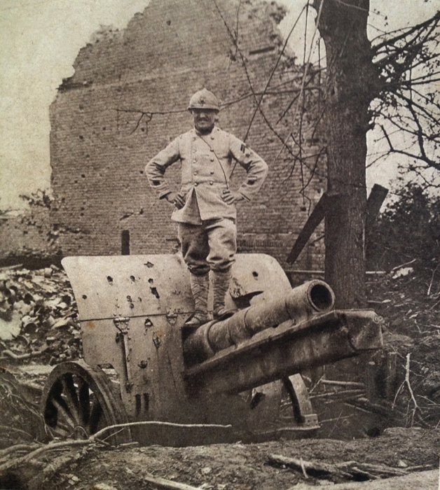 A telephonist stands perches on top of a German 77 mm gun in 1918.