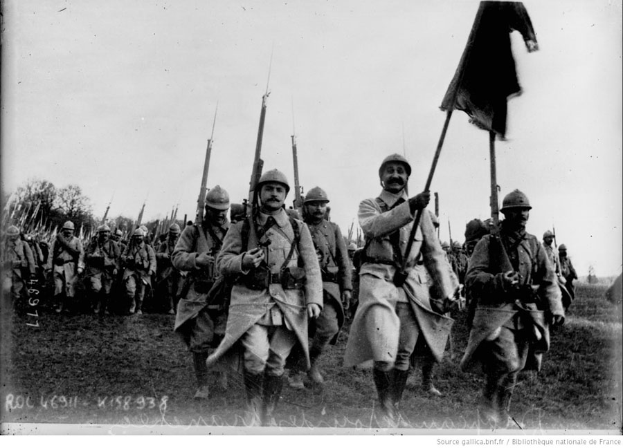 A column parades past the camera with regimental colors unfurled.