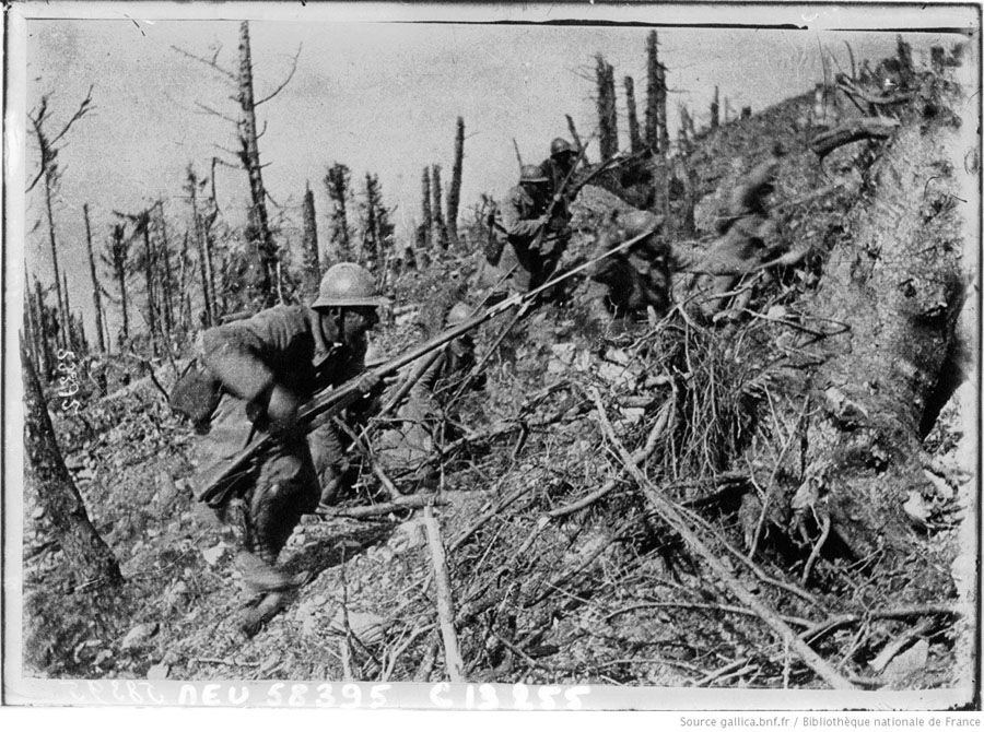 Combat photo of French troops (possibly 152 RI) advance up the scarred slope of a hill in the Argonne.