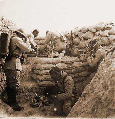 Soldiers quickly putting on their gas masks. Note the man on the left carrying a flame-thrower.