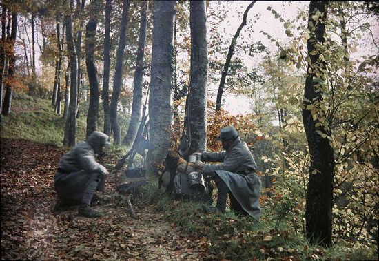 Two poilus huddle around a small cooking-fire.