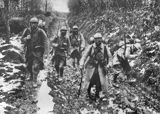 Soldiers make their way through a muddy road.