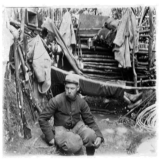 These men have arranged a make-shift hammock in their trench using tree limbs and a tent canvas. 1915.