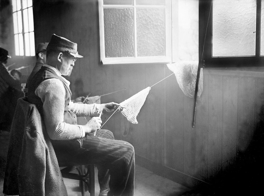 A blinded soldier works on a piece of crochet.