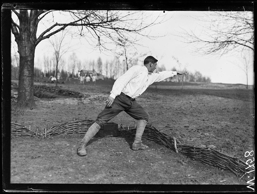 An instructor demonstrates the correct aiming position taken before lobbing a grenade.