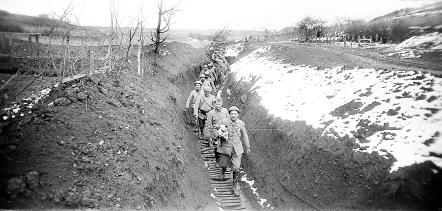 A work detail moves through a snowy trench in Nancy. Note the dog in the arm of the man in front that serves as both companion and rat-killer.