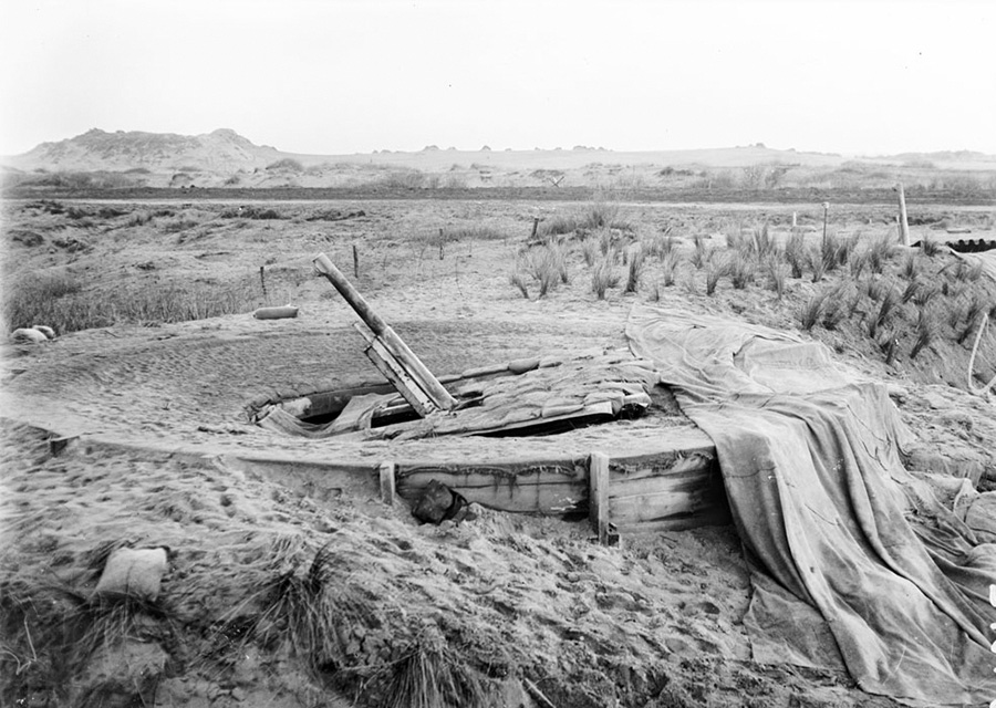 A camouflaged gun entrenched in the sand and covered with netting on the beaches of Nieuport, 1916.