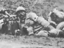 Photo taken during an actual attack. Columns lie prone in reserve as an assault wave [center background, behind the bush] advances. A medic lies down facing the camera in the center of the frame.
