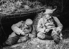 Two soldiers making trench rings in their spare time in front of their shelter.