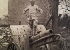 A telephonist stands perches on top of a German 77 mm gun in 1918.