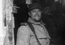 A soldier smiles at the photographer as he stands with his comrades in a covered trench, early 1915.