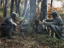 Two poilus huddle around a small cooking-fire.