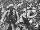 Soldiers make their way through a muddy road.