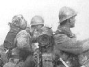 Soldiers man the parapet of a recently conquered trench amid debris and a German corpse.