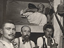 Soldiers playing cards and smoking pipes in a shelter.