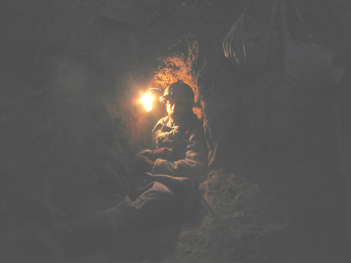 Sgt. Contamine in a small shelter uses a improvised lantern made from a sardine tin to see in the night.