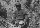 A French soldier wearing a mourning arm band poses beside a skull. 