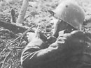 German rifleman takes cover next to some half-buried French corpses.