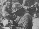 A soldier casually examines a skull.