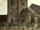 A small military cemetery stands in front of a destroyed church.