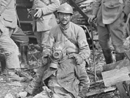 A stretcher-bearer props up a dead German soldier.